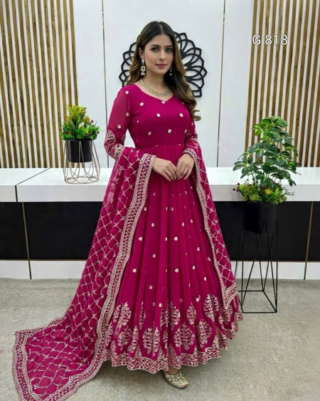 Woman in a pink traditional outfit with intricate designs in an indoor setting.