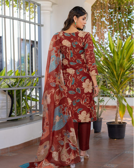 Woman wearing a floral outfit standing on a balcony with plants in the background