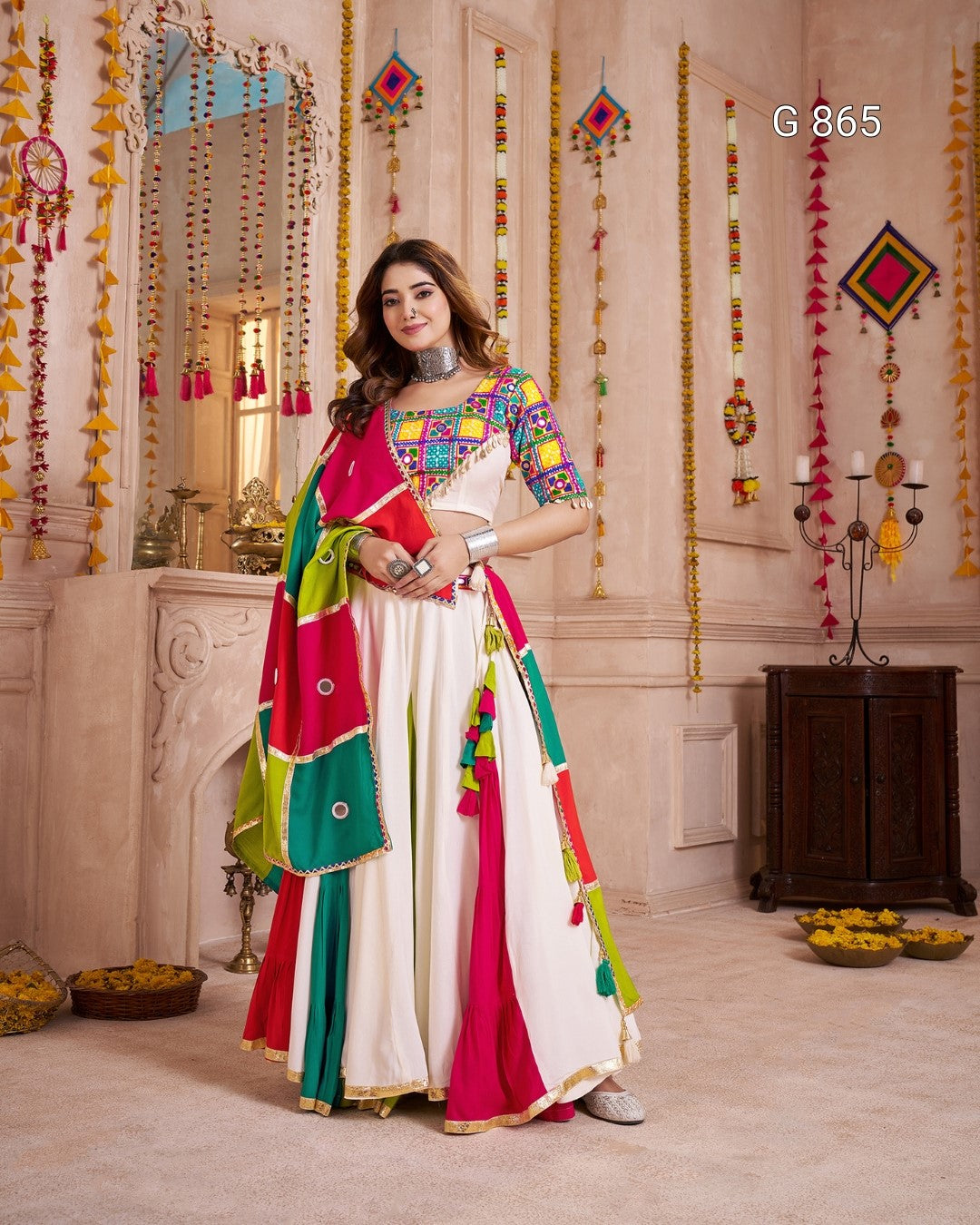 Woman in a colorful traditional outfit standing in a decorated room.