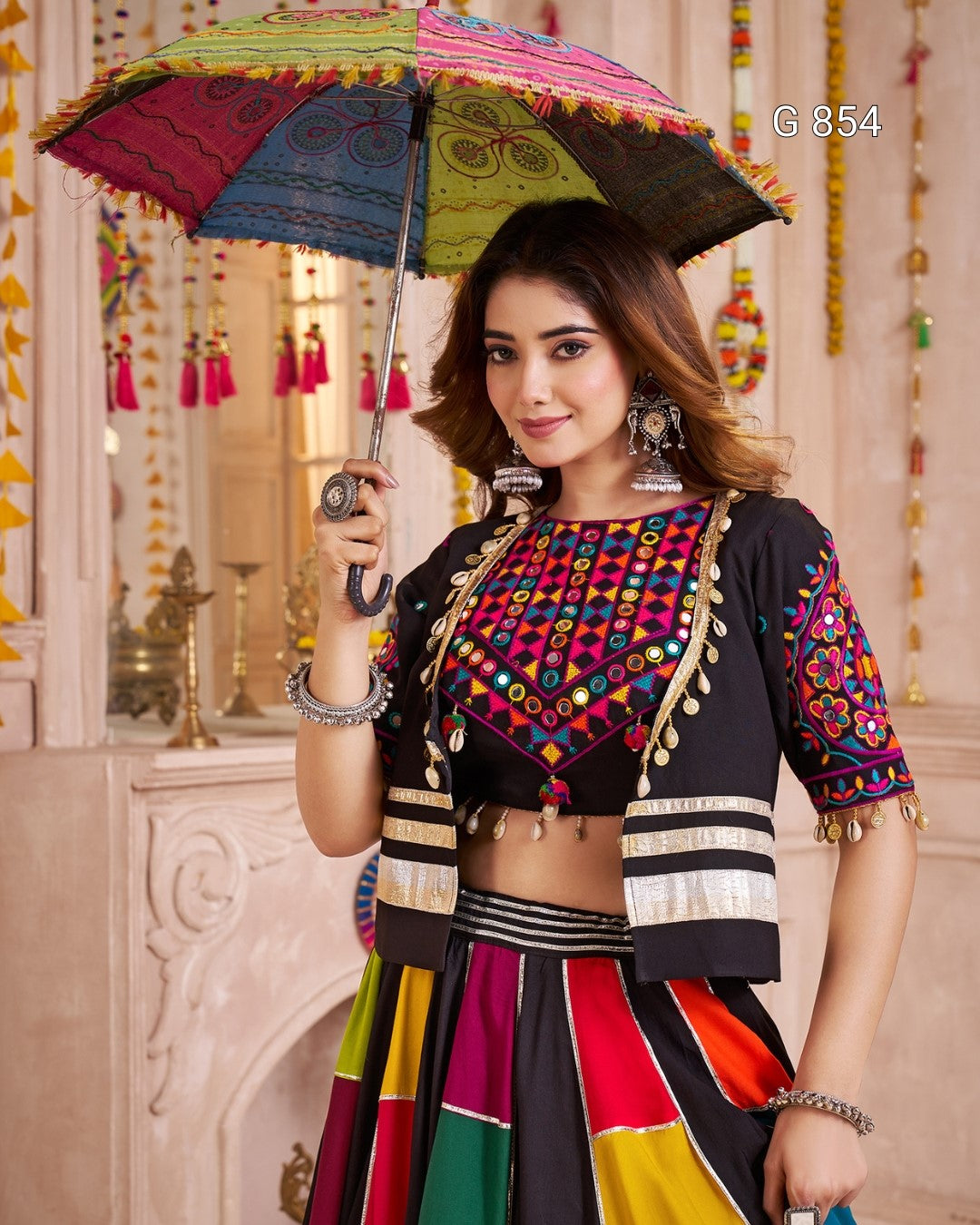 Woman in traditional outfit holding a colorful umbrella with decorative patterns.