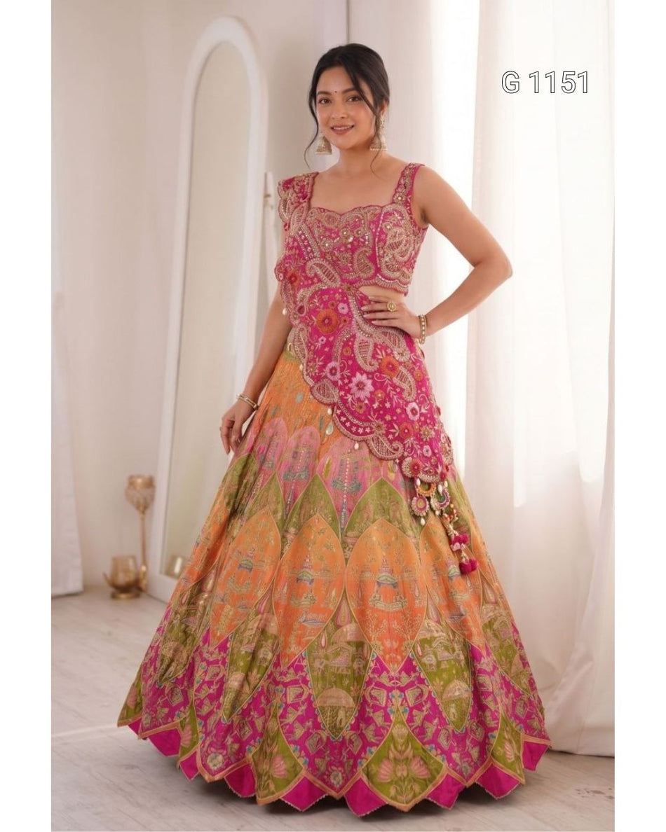 A woman modeling a traditional Indian lehenga choli outfit with intricate embroidery. The outfit features a bright pink choli and a voluminous skirt in shades of orange, pink, and green with detailed patterns.