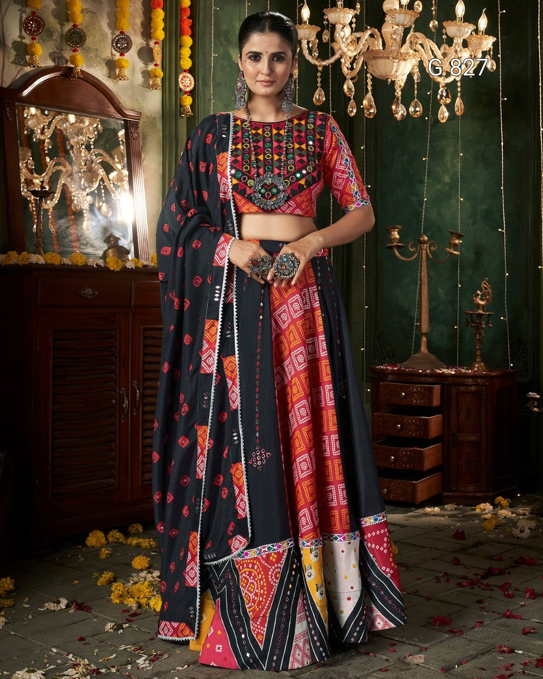 Woman in a colorful traditional outfit standing in a decorated room with a chandelier.