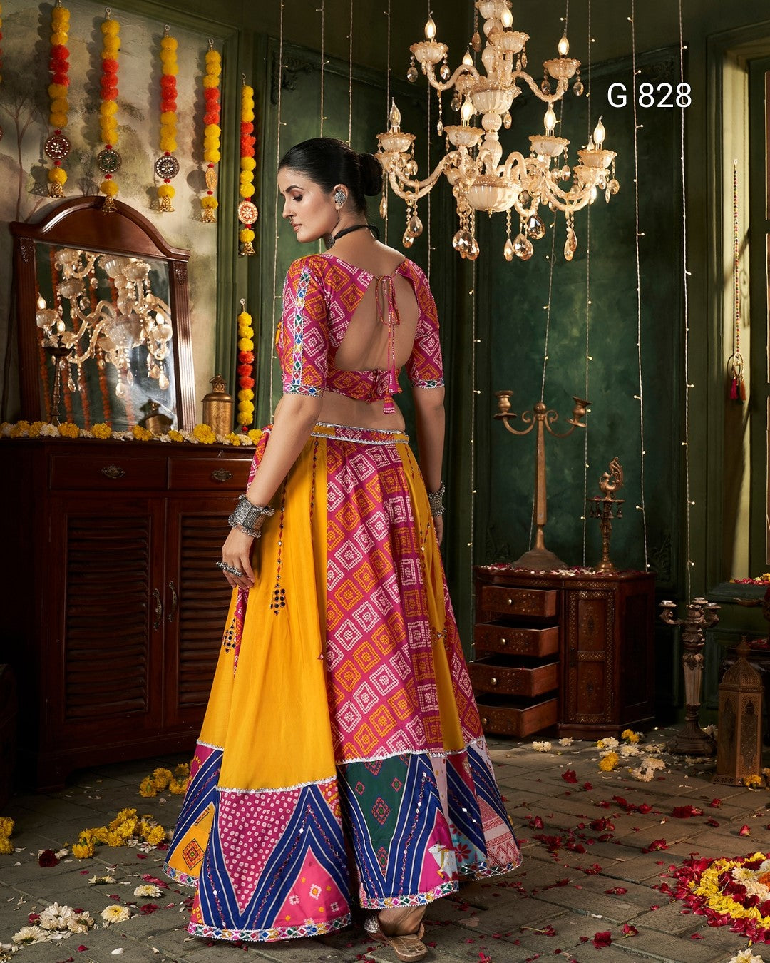 Woman in a colorful traditional outfit standing in a decorated room with a chandelier.