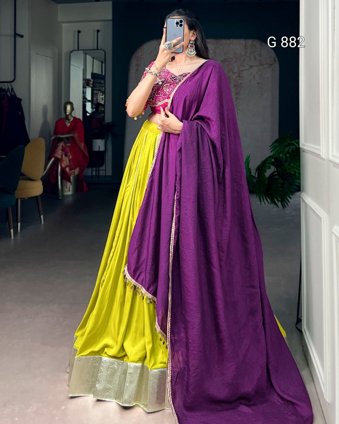Woman wearing a yellow saree with a purple dupatta in a room.
