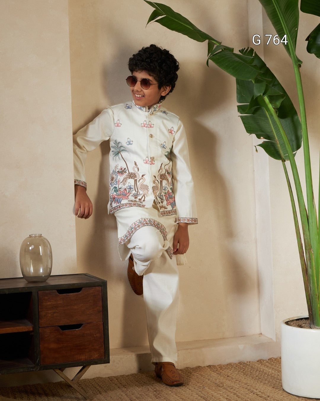 Child wearing a traditional outfit with a plant and wooden cabinet in the background