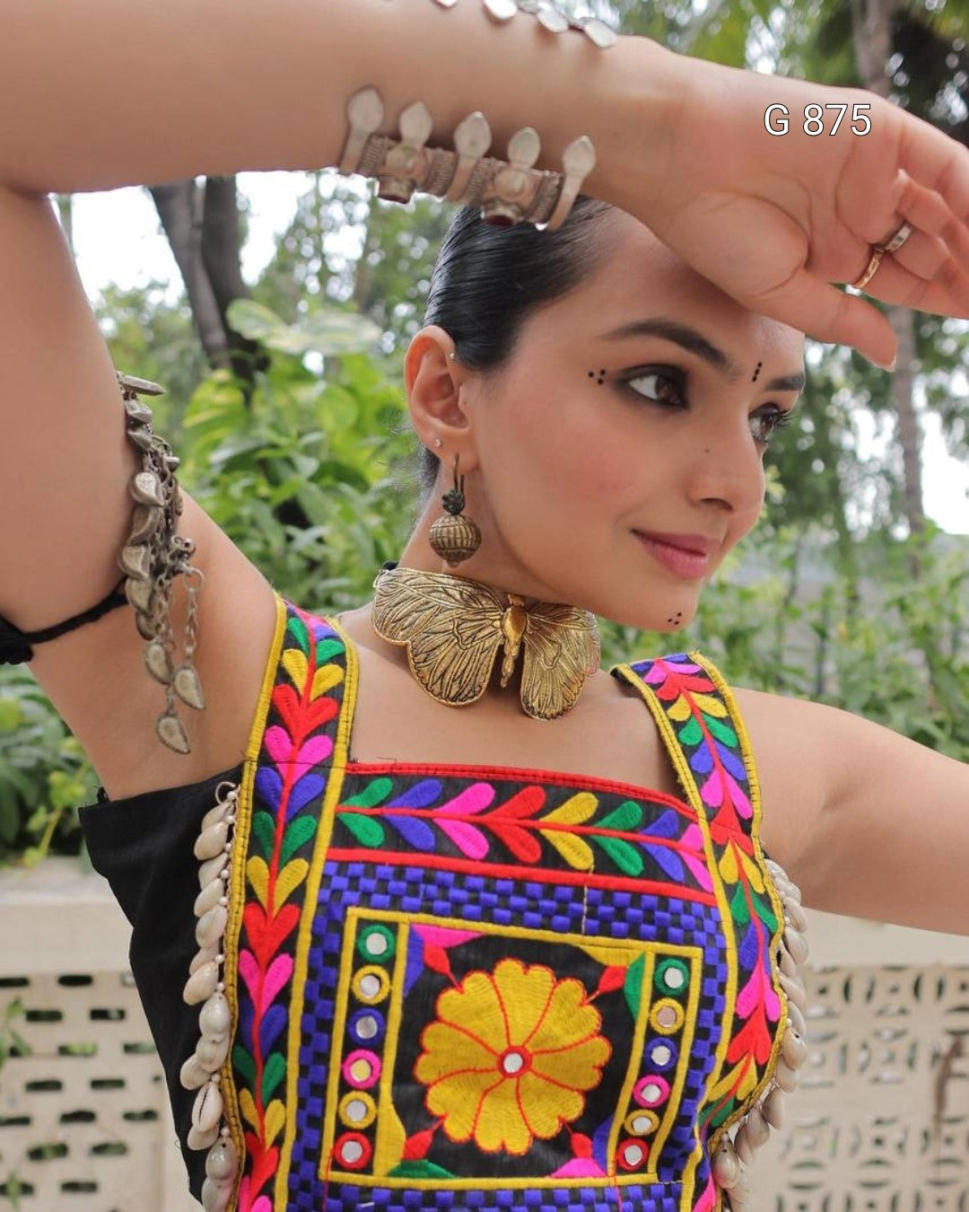 Woman wearing a colorful traditional outfit with intricate designs and jewelry.