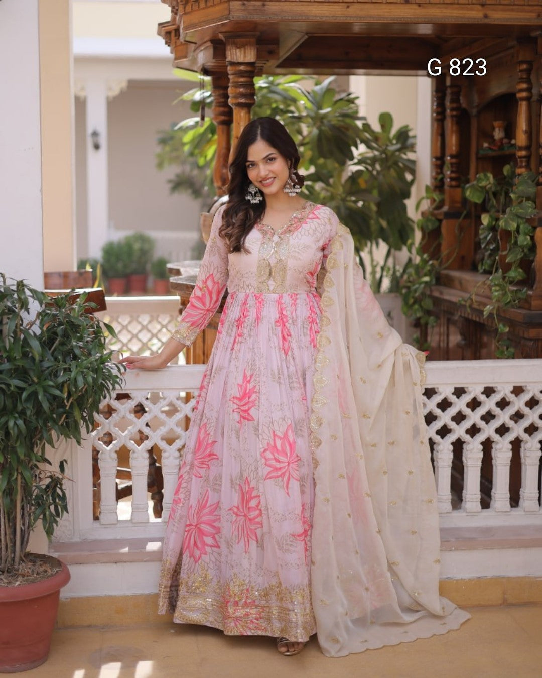 Woman in a traditional outfit with pink floral patterns standing in an outdoor setting.