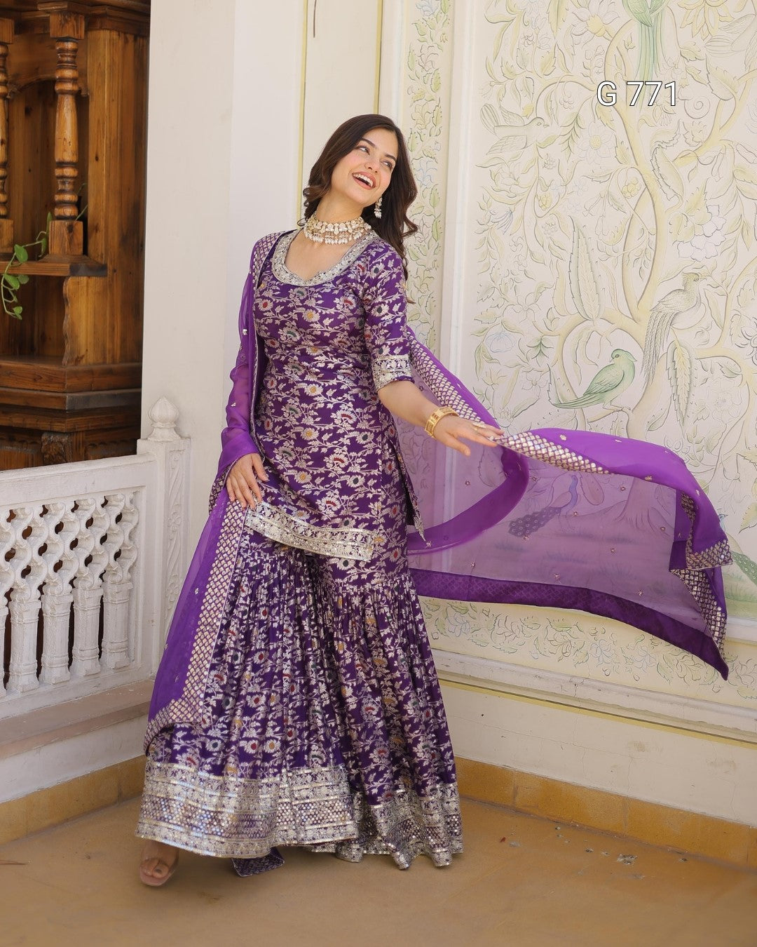 Woman in a purple traditional outfit with a matching dupatta in an ornate room.