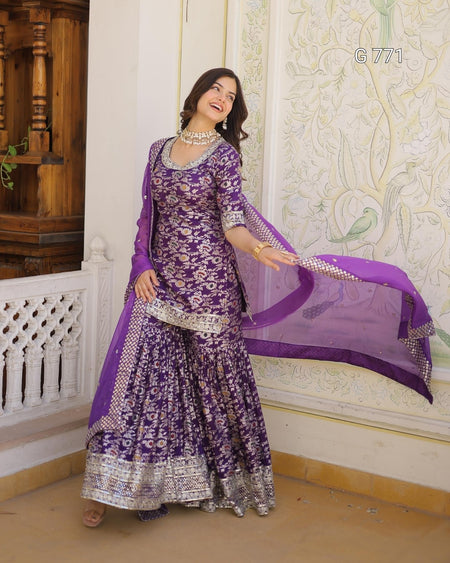 Woman in a purple traditional outfit with a matching dupatta in an ornate room.