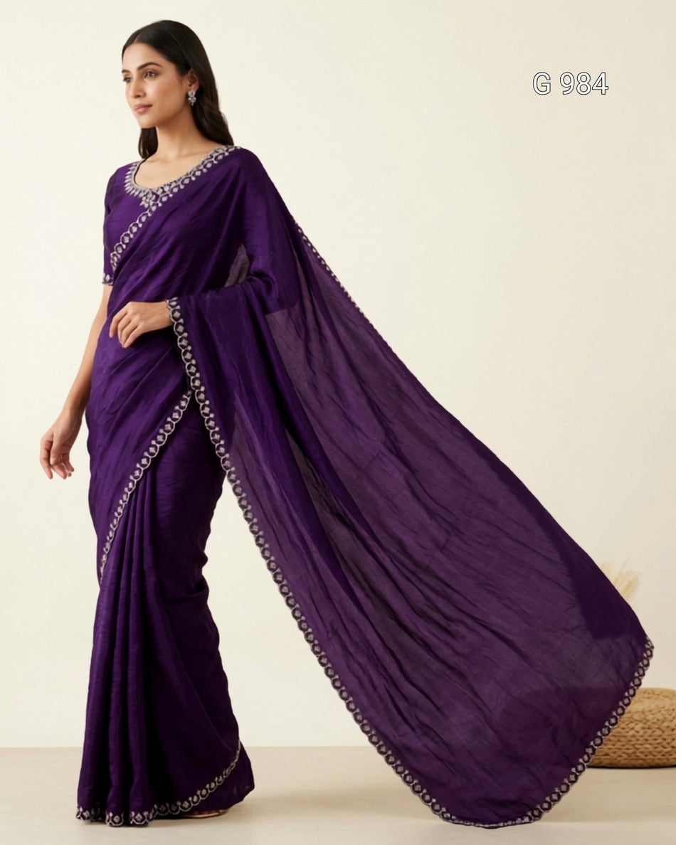 A woman modeling a deep purple sari with silver embroidered borders, set against a plain cream background. The text 'G 984' is visible in the top right corner.