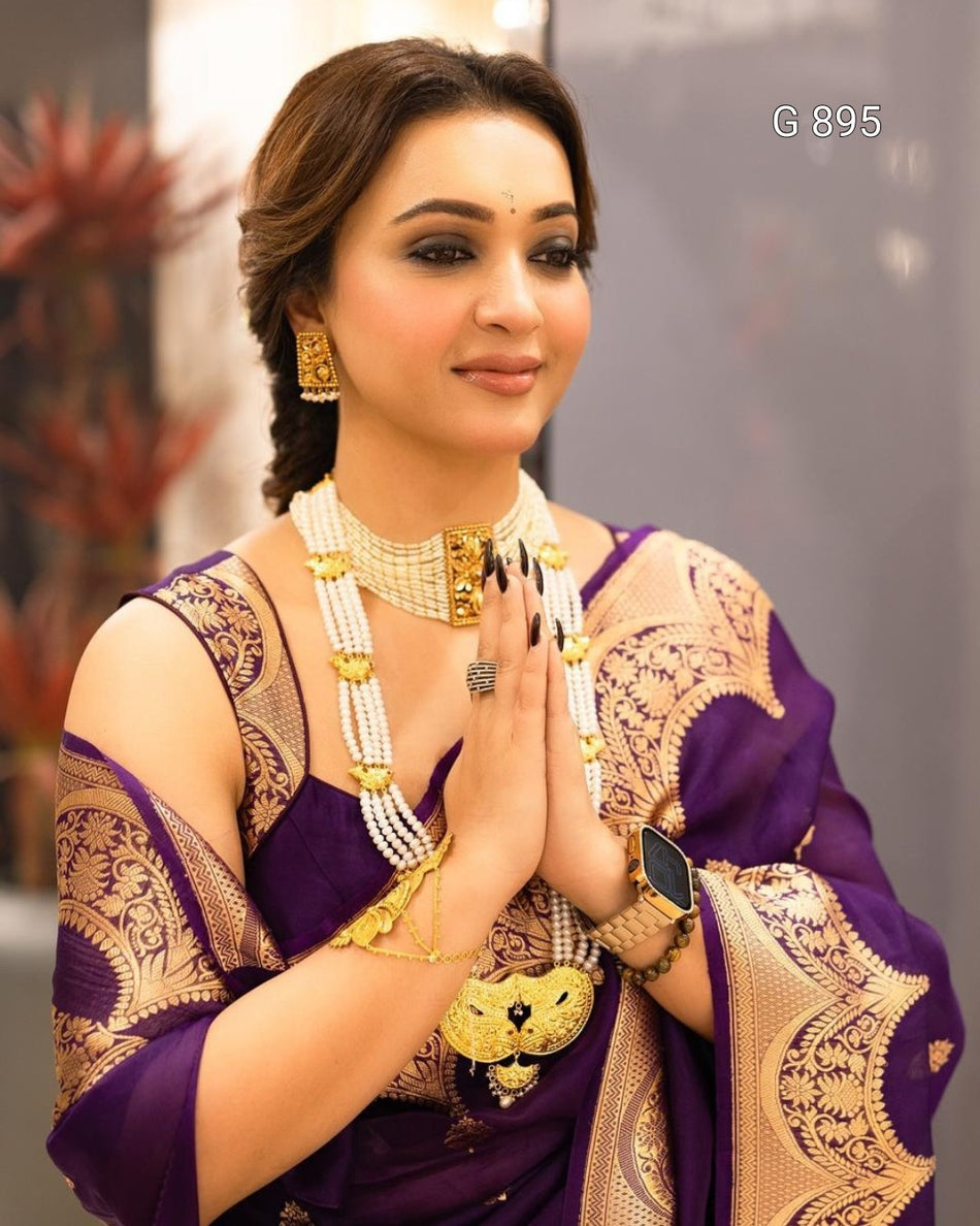 Woman in traditional attire with gold jewelry, posing indoors.