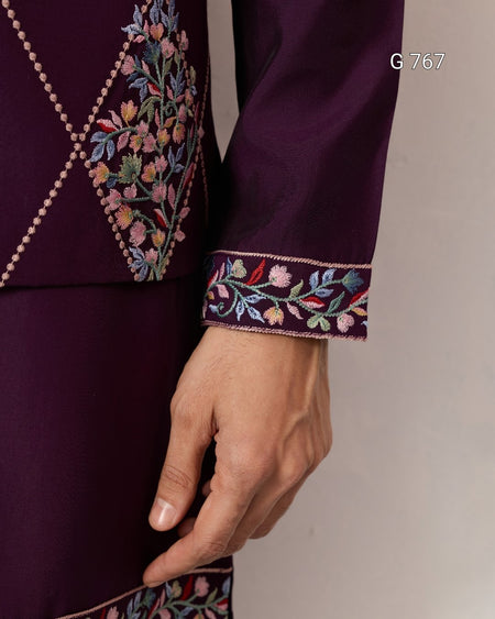 Close-up of a purple garment with intricate floral embroidery on a plain background