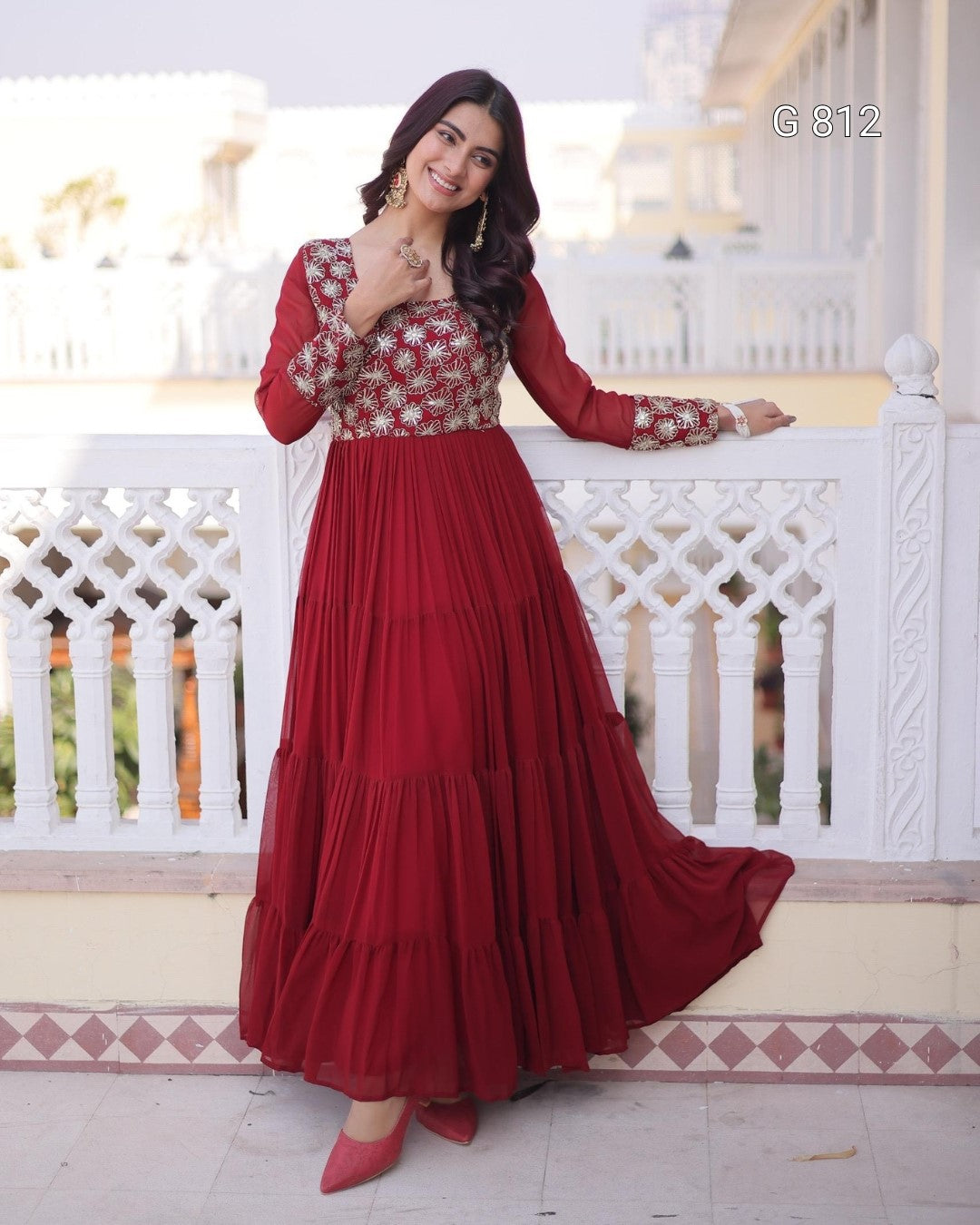 Woman in a red and white traditional outfit standing on a balcony.