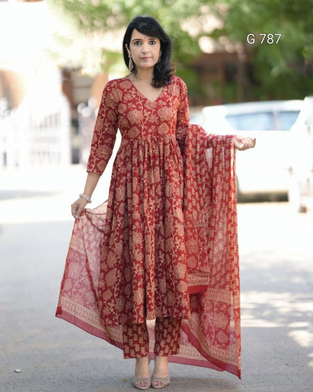 Woman wearing a red patterned dress with a matching dupatta outdoors.