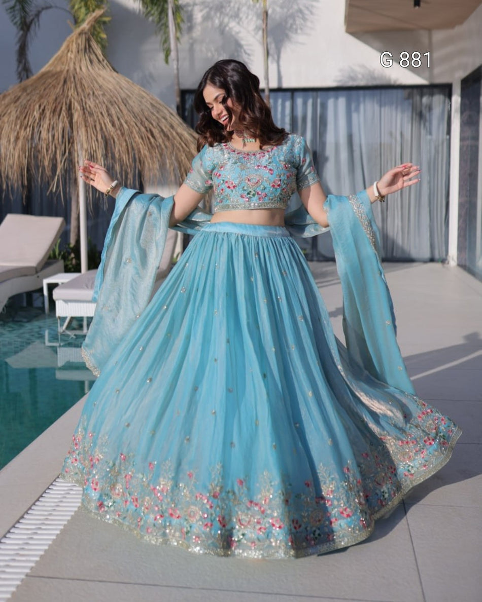Woman in a light blue traditional outfit with floral patterns by a poolside.