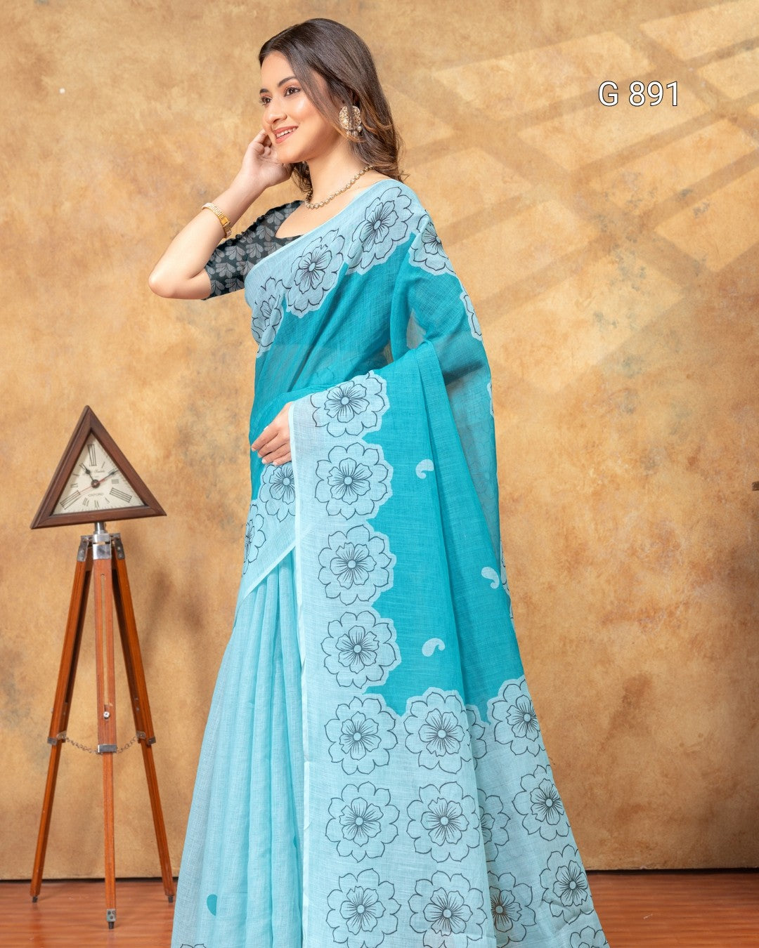 Woman wearing a blue saree with floral patterns against a brown background