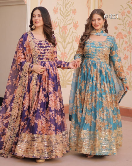 Two women wearing floral dresses standing against a decorative wall.
