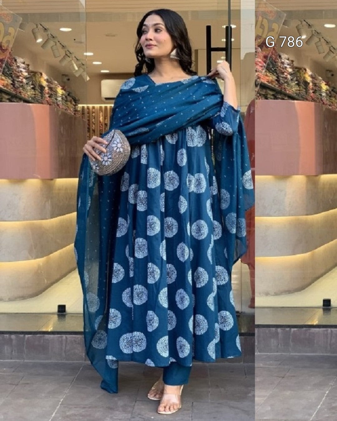 Woman wearing a blue patterned outfit with a matching shawl in a store setting.