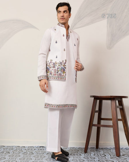 Man wearing a traditional white embroidered kurta with a wooden stool in the background