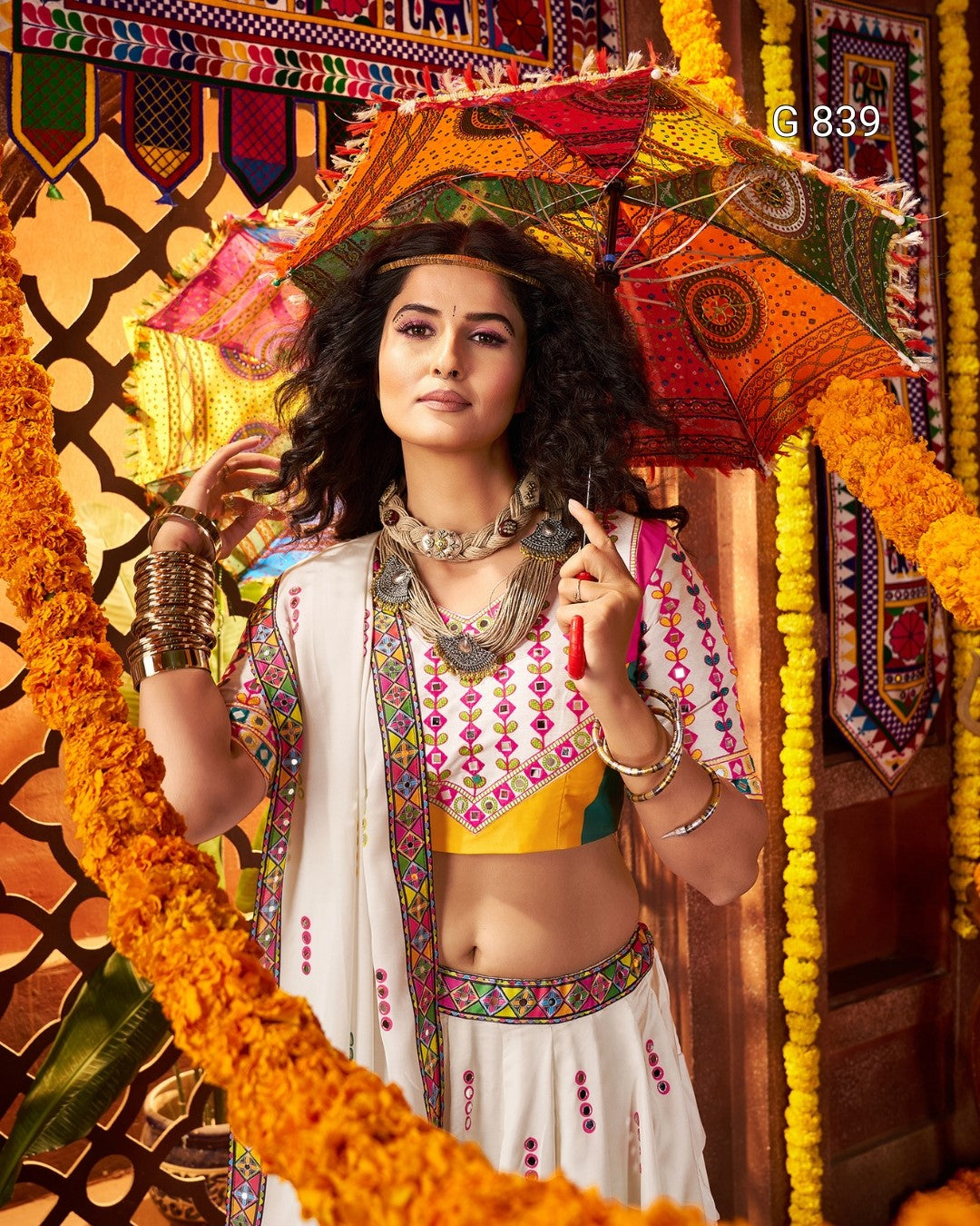 Woman in traditional attire holding a colorful umbrella with decorative background