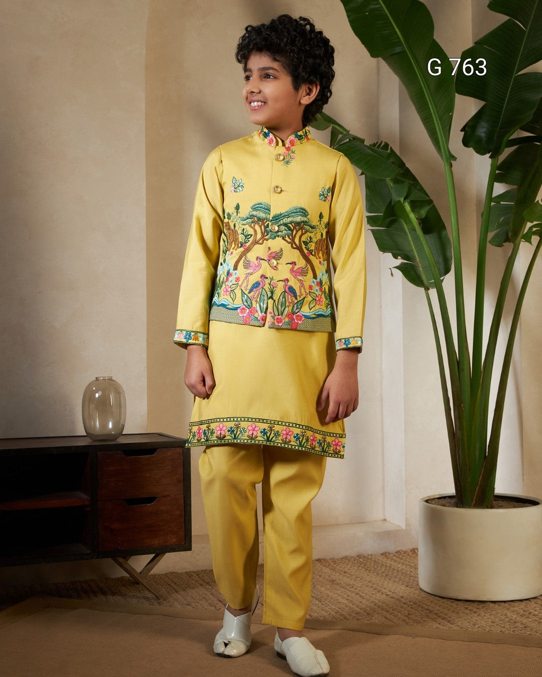 Child wearing a yellow traditional outfit with floral patterns in a room setting.