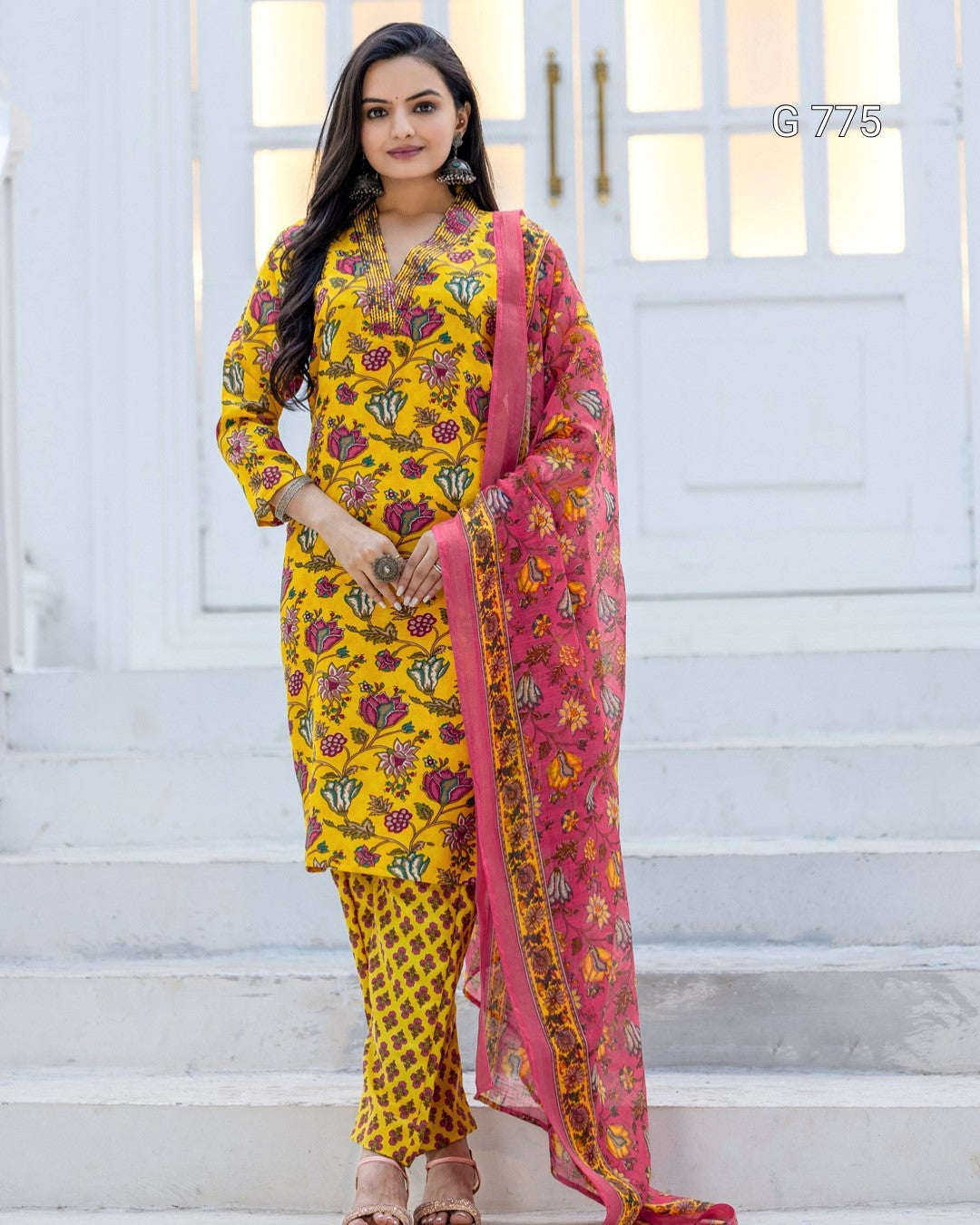 Woman wearing a yellow floral outfit with a pink dupatta on a white background