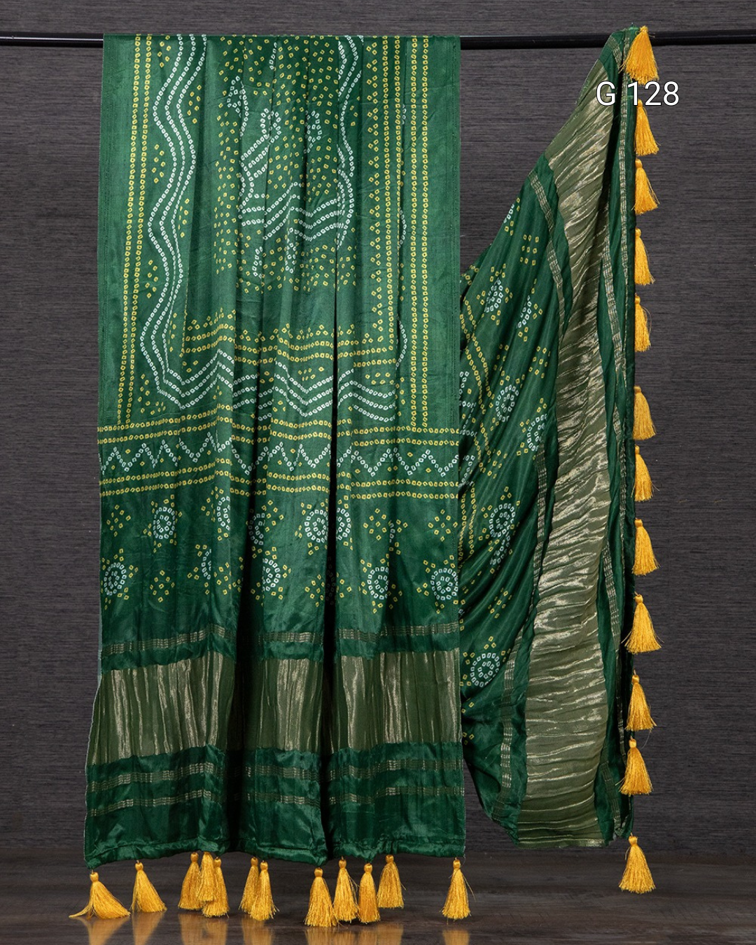 Green saree with yellow patterns and tassels on a dark background