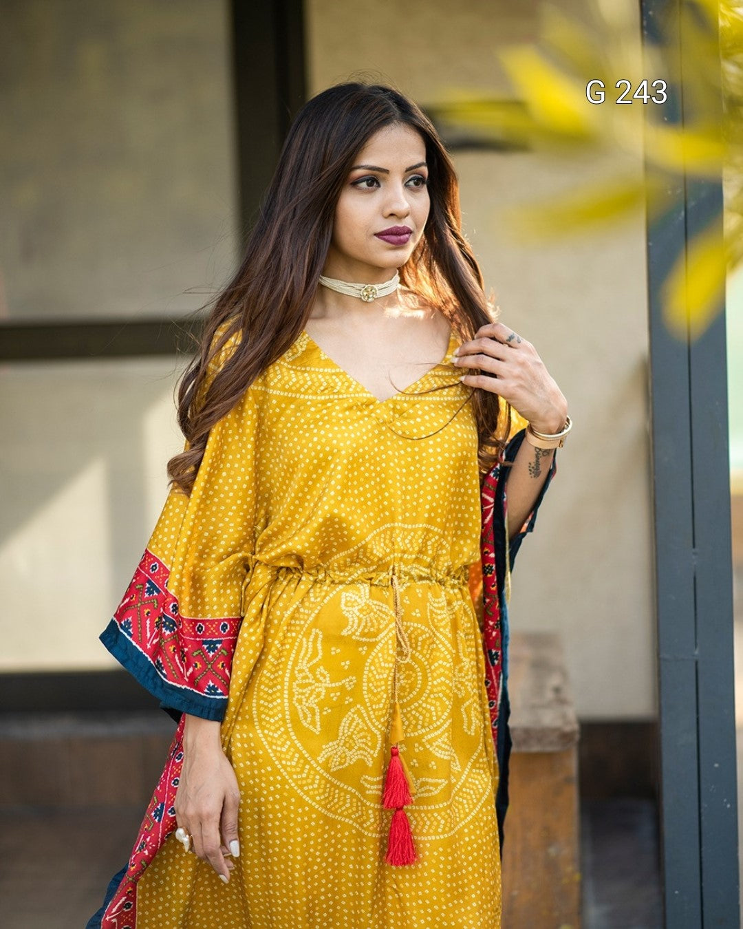 Woman wearing a yellow dress with red accents, standing outdoors.