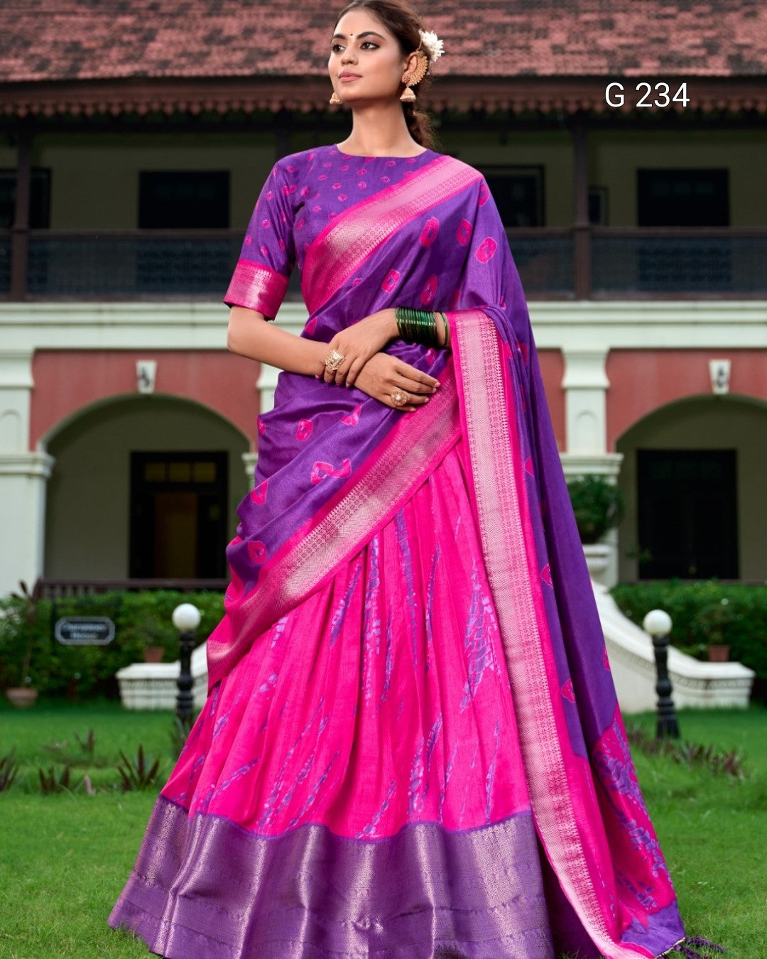 Woman wearing a pink and purple saree with a building in the background