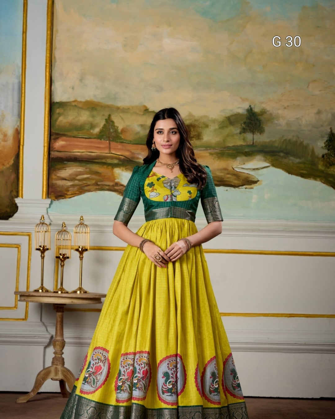Woman in a yellow and green dress with floral design standing in front of a painting.