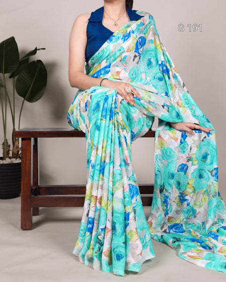 Woman sitting on a bench wearing a floral saree with a blue blouse.