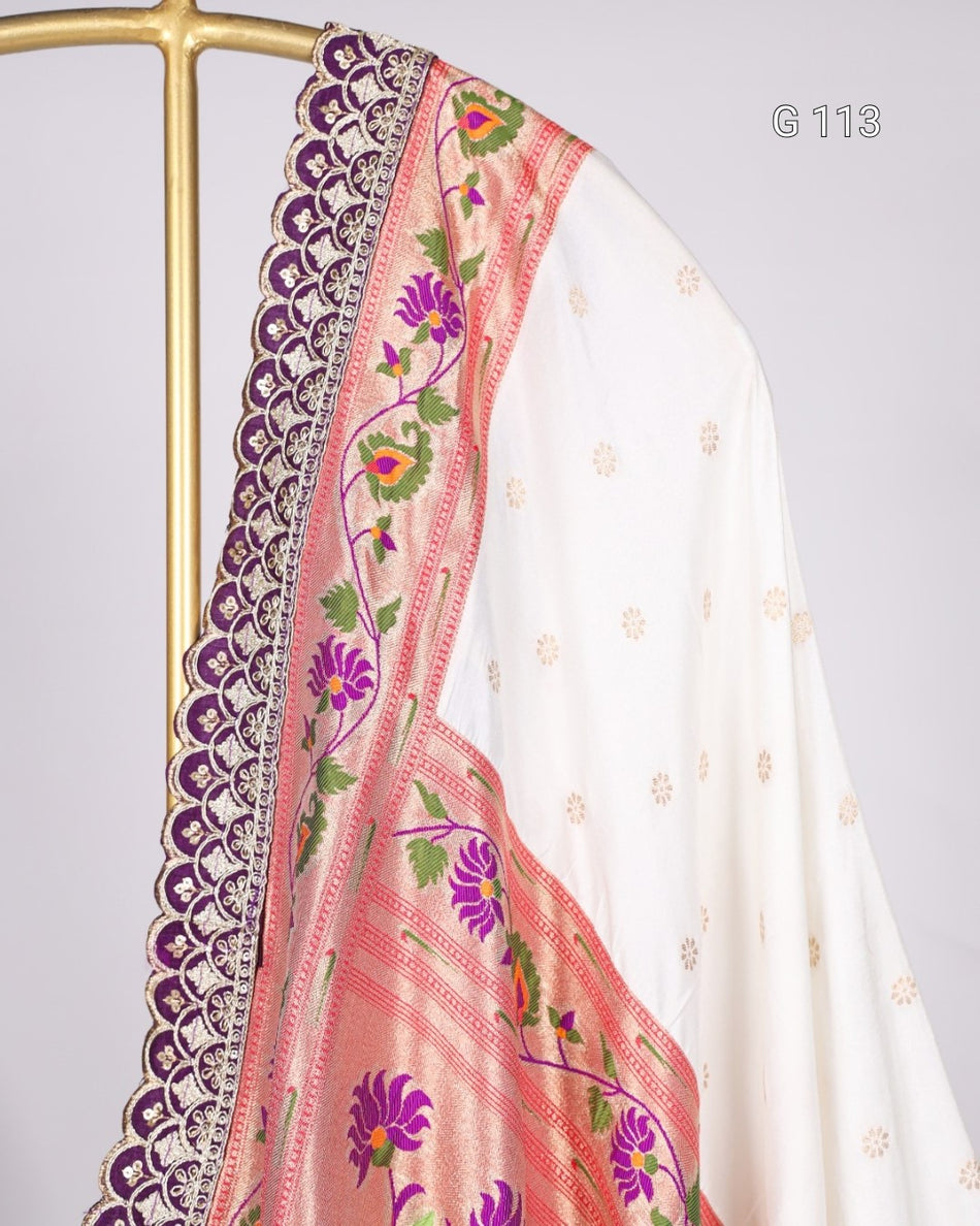 White saree with pink and purple floral embroidery on a gray background