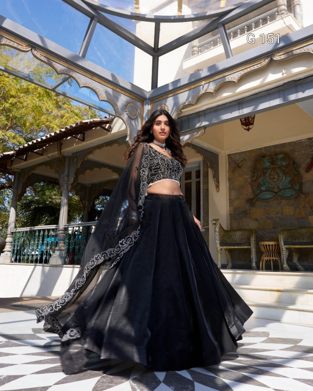 Woman in a black traditional outfit standing in an outdoor setting with architectural elements.