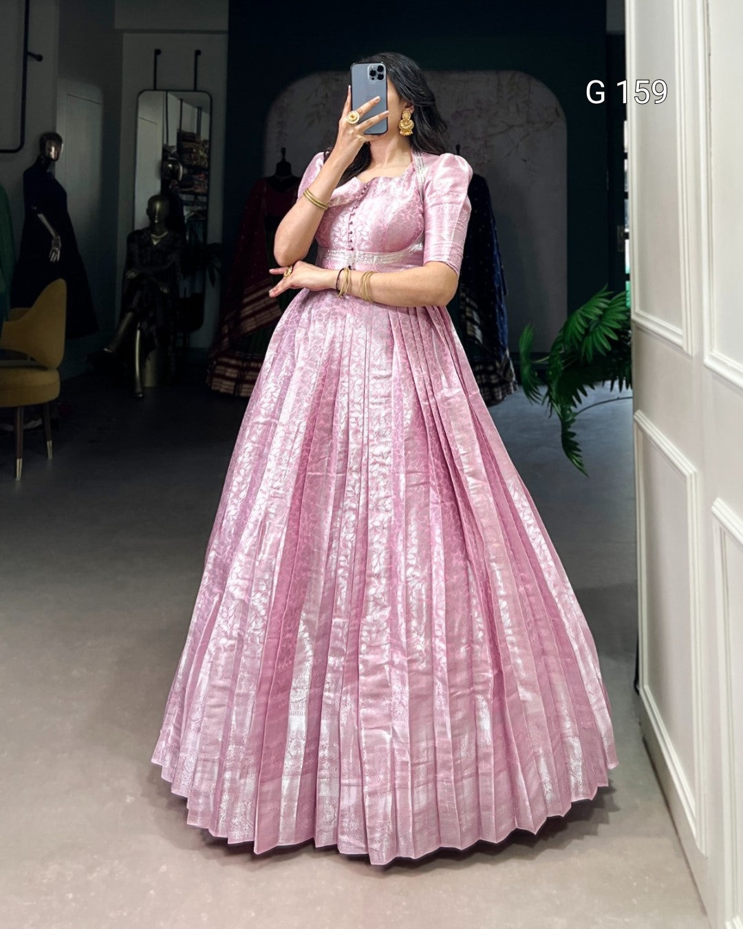 Person wearing a pink dress taking a mirror selfie in an indoor setting.
