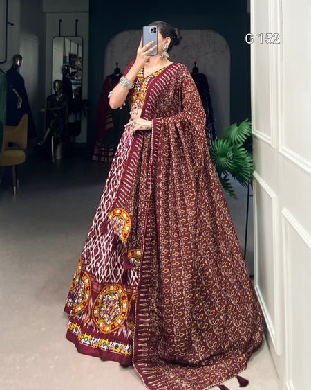 Person wearing a traditional maroon and gold saree with a patterned design, standing indoors.