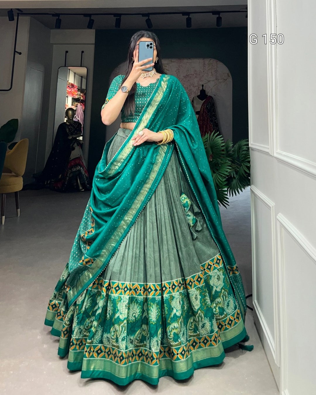 Person wearing a green and blue traditional outfit in a room.
