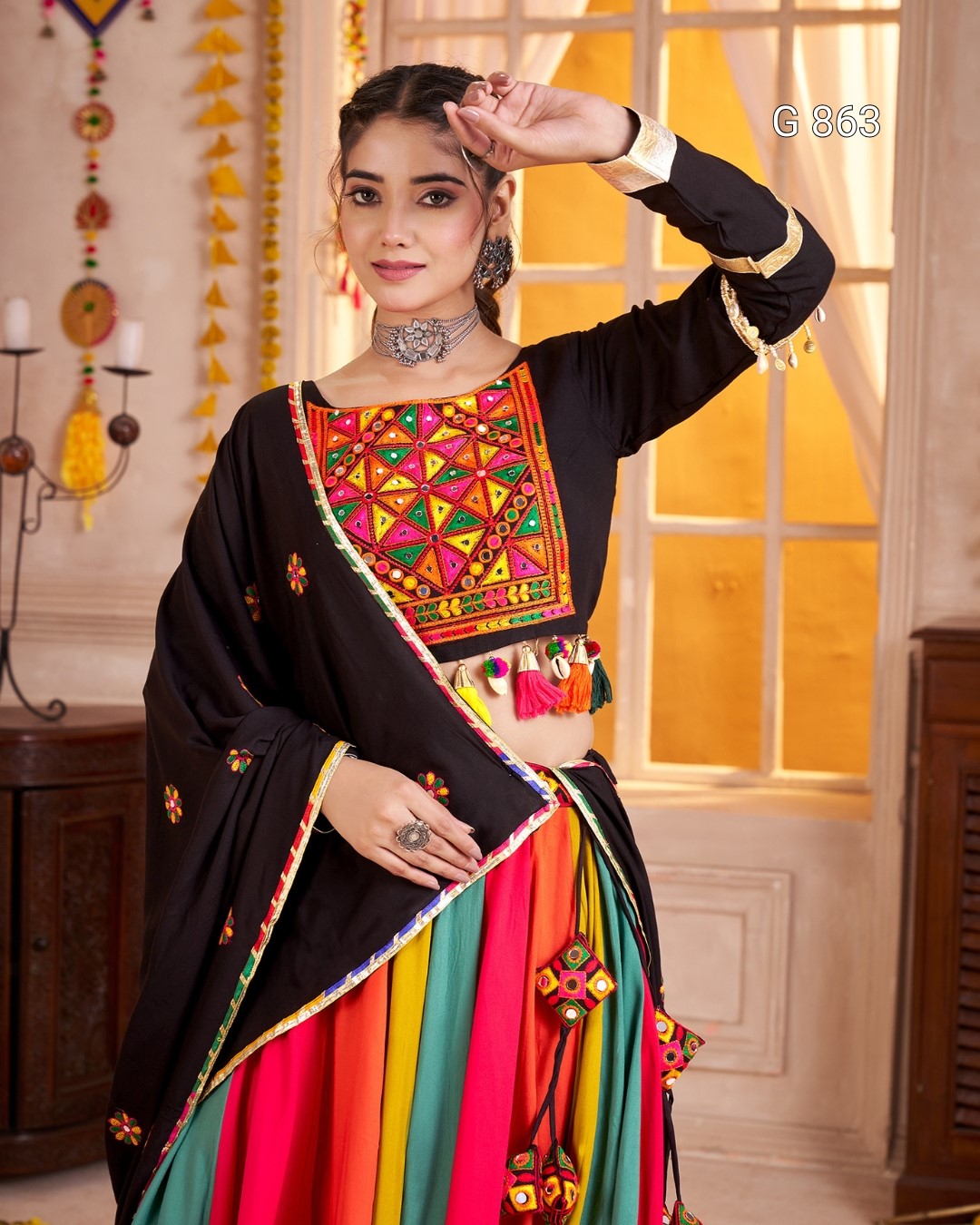 Woman wearing a traditional outfit with colorful embroidery in a decorated room.