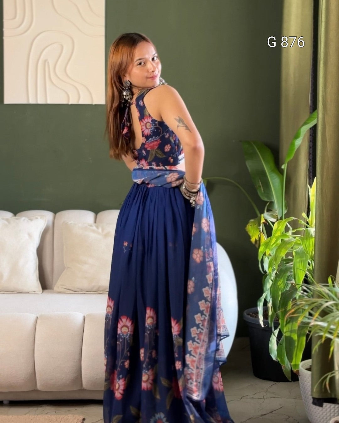 Woman in a floral dress standing in a living room with a green wall and white sofa.