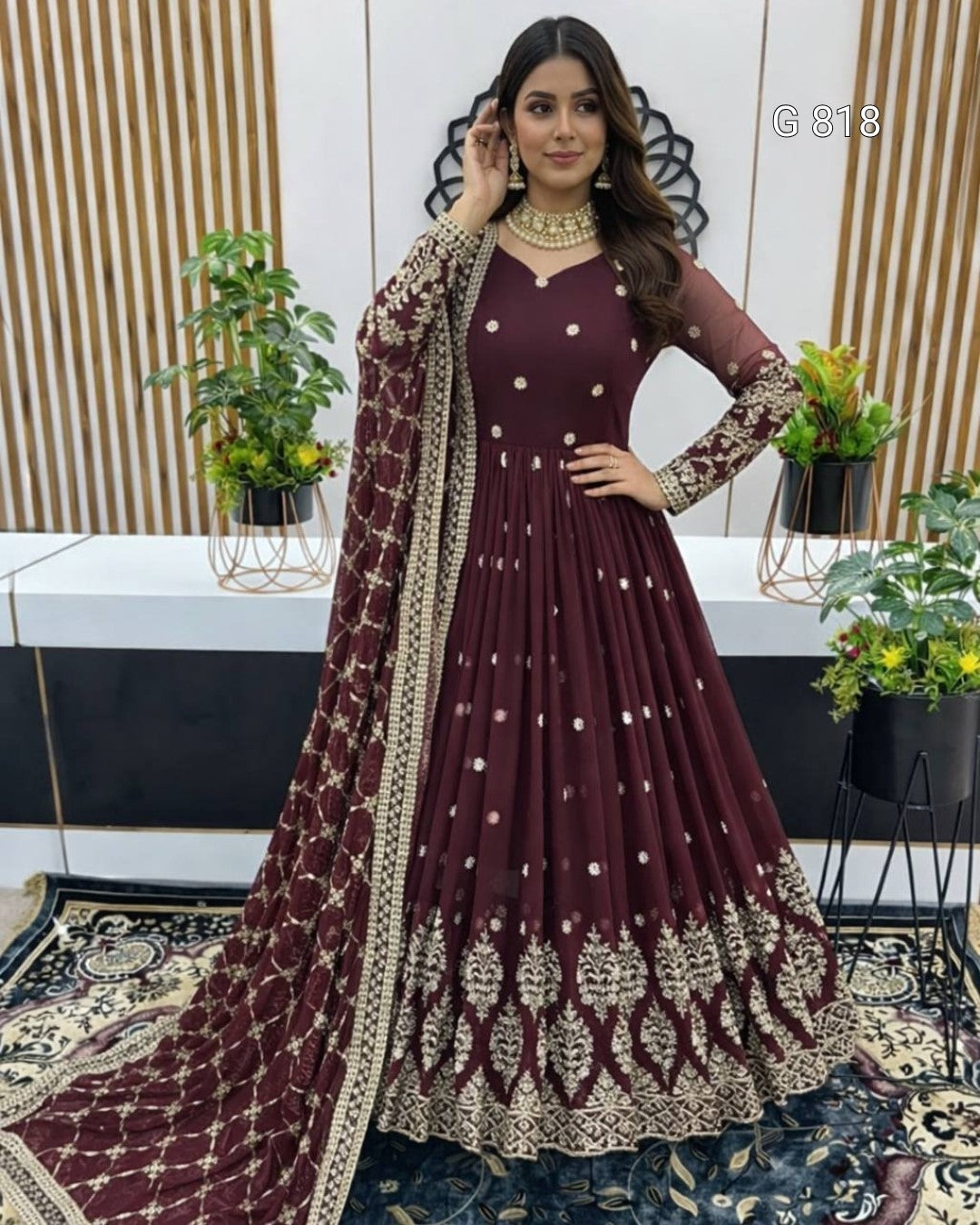 Woman in a maroon traditional outfit with gold embroidery in an indoor setting.
