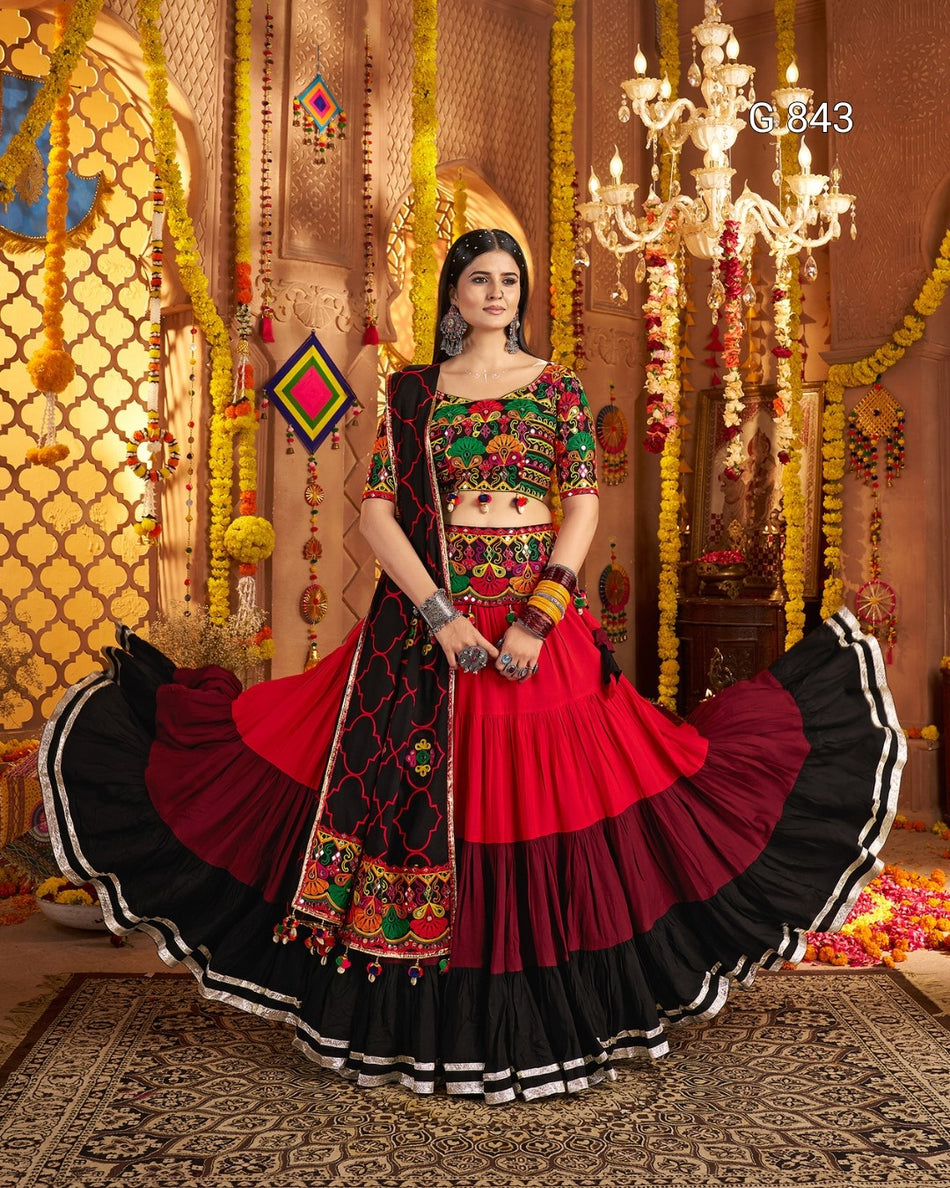 Woman in a traditional red and black embroidered outfit in a decorated indoor setting.