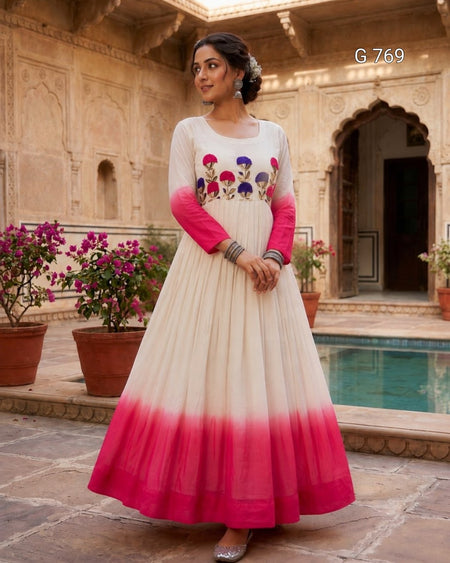 Woman in a white and pink dress with floral design standing in front of an architectural background.