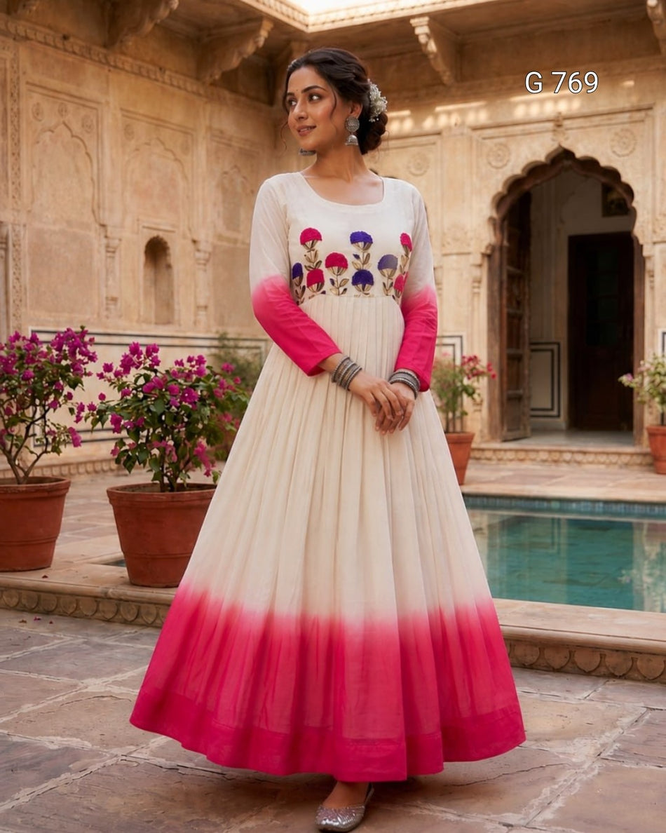 Woman in a white and pink dress with floral design standing in front of an architectural background.