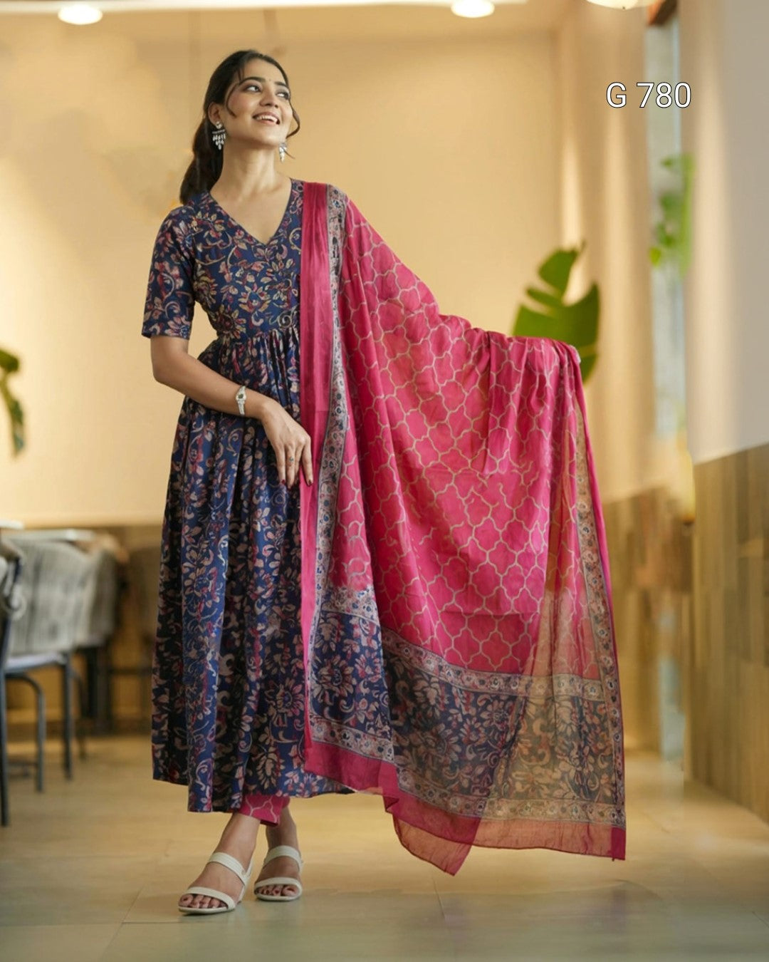 Woman in a floral dress with a pink dupatta in an indoor setting
