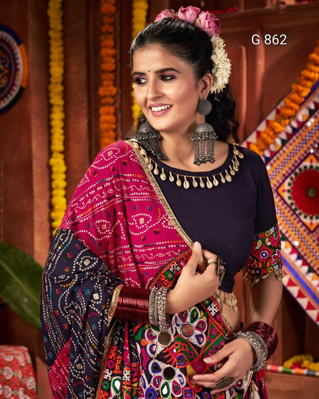 Woman in traditional outfit with colorful patterns and jewelry against a decorative background