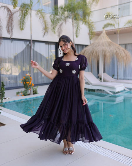 Woman in a dark purple dress standing by a pool with a blurred background