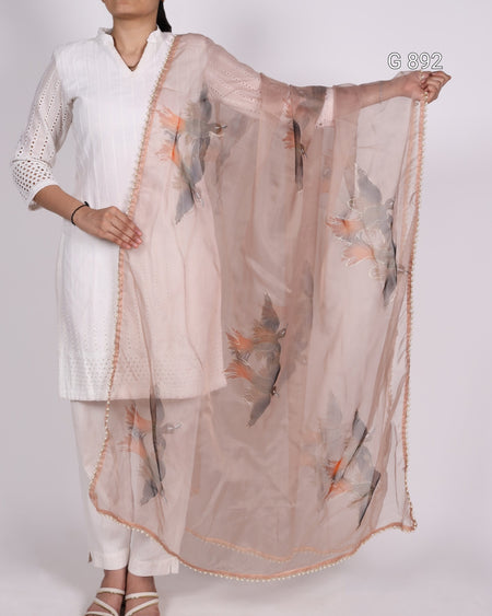 Woman wearing a white kurta with a sheer dupatta featuring bird prints on a plain background