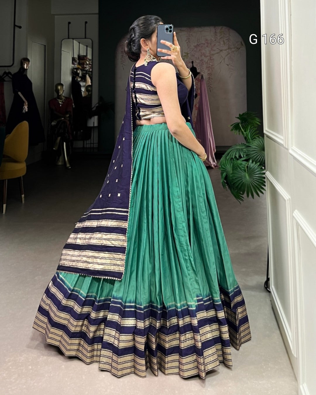 Woman taking a mirror selfie wearing a traditional outfit with a green skirt and navy top.