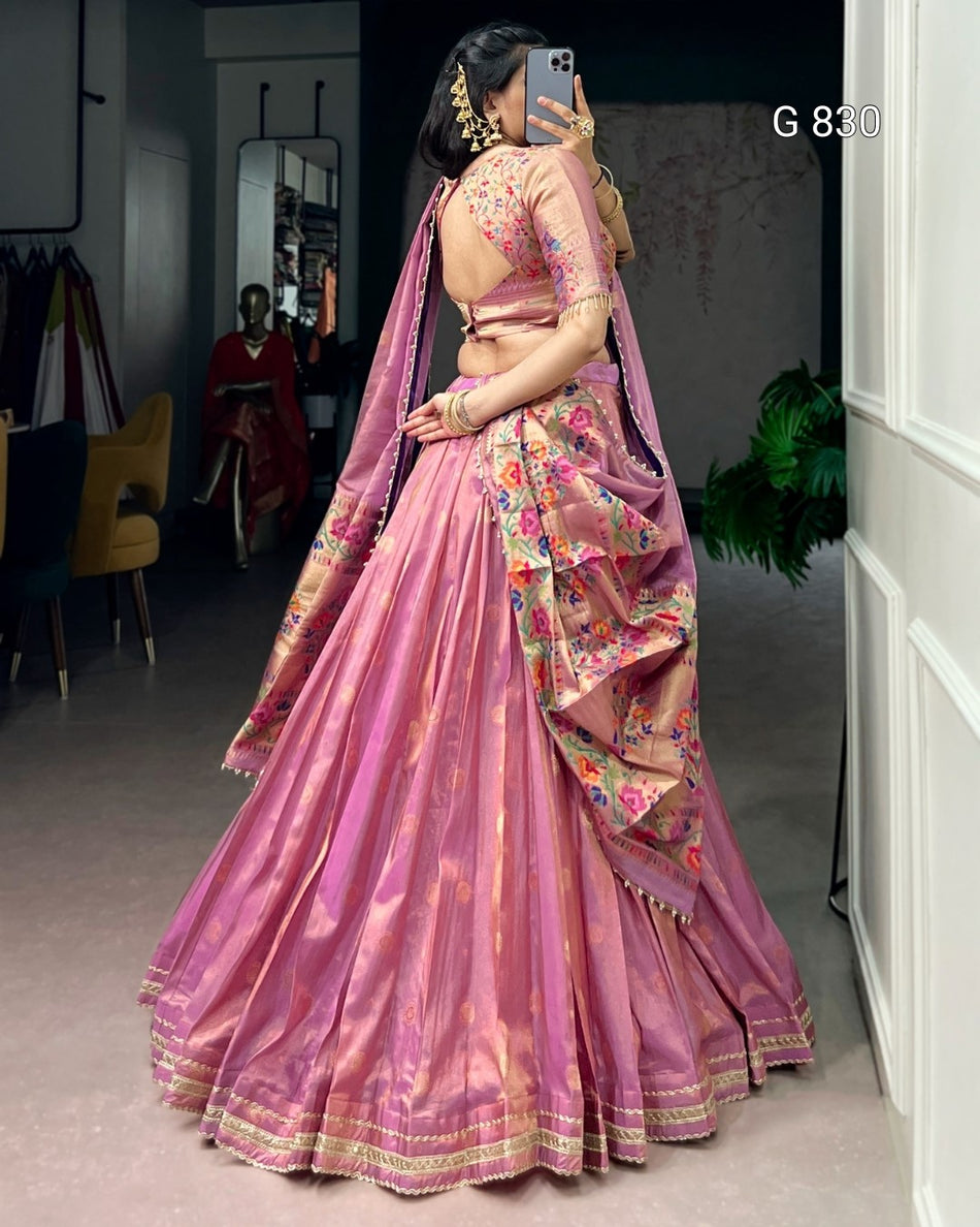 Woman in a pink saree with floral patterns taking a mirror selfie.