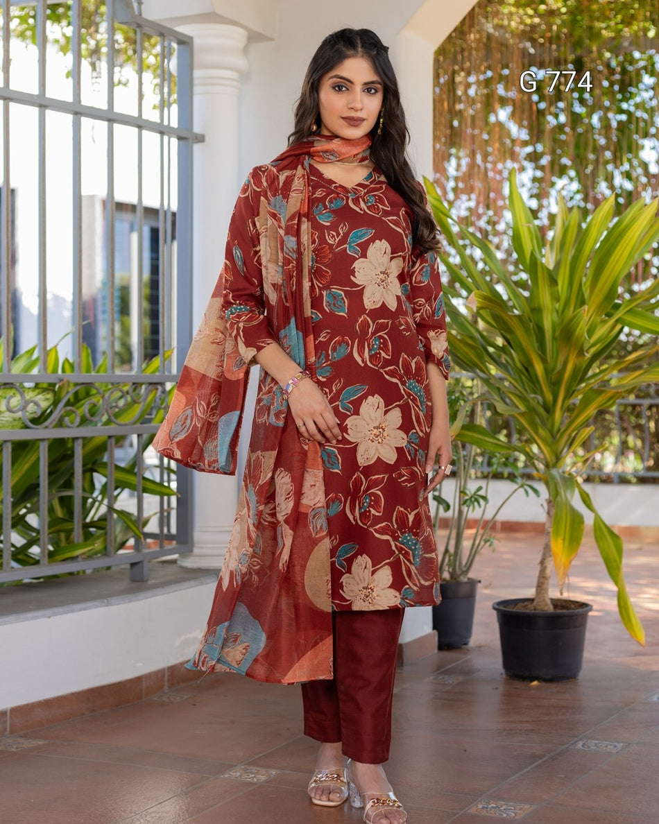 Woman wearing a floral red outfit standing on a balcony with plants.