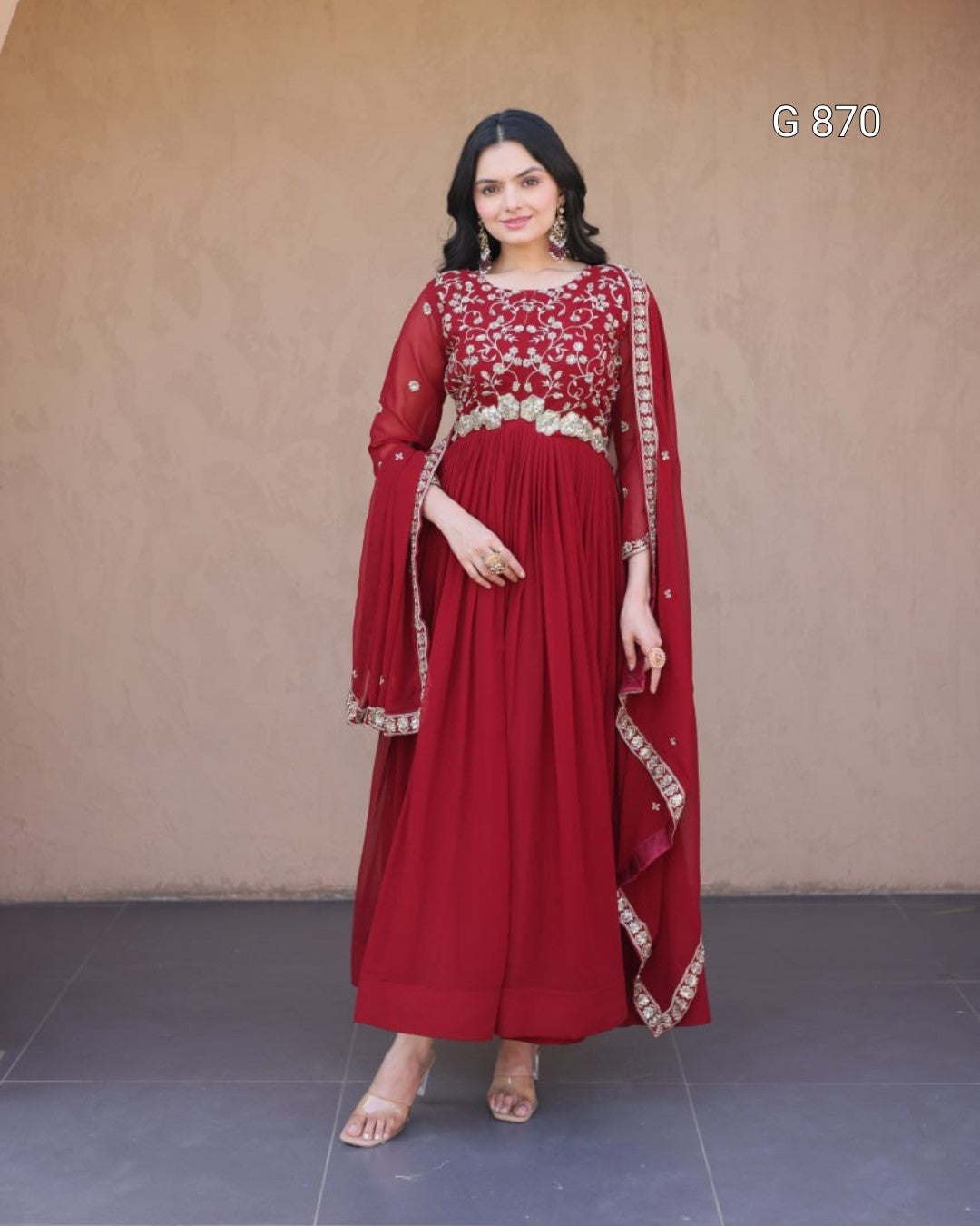 Woman wearing a red traditional outfit with white embroidery against a plain background